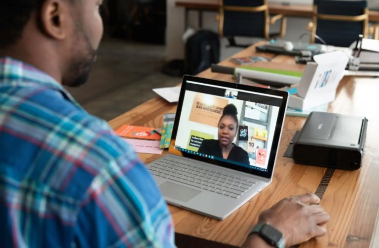 Image of a man sitting at a table using a laptop to access online therapy. Discover the impact online therapy in Parkland, FL and how it can help you overcome your mental health struggles.