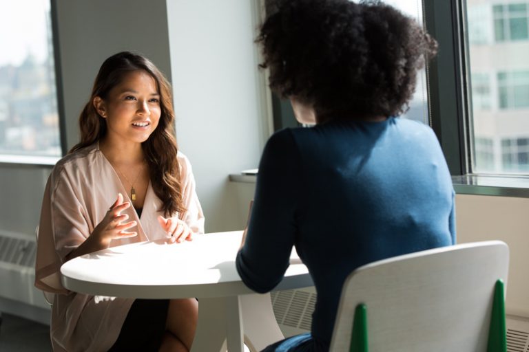 Photo of two women siting at a table smiling and talking. Are your anxiety symptoms taking over? With the help of a skilled anxiety therapist you can begin coping with your symptoms in a healthy way with anxiety therapy in Coconut Creek, FL.