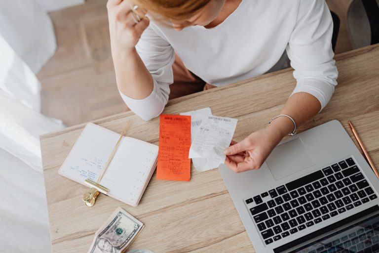 Image of a stressed woman working on laptop and holding papers. Discover how anxiety therapy in Parkland, FL can help you manage your stress due to inflation.