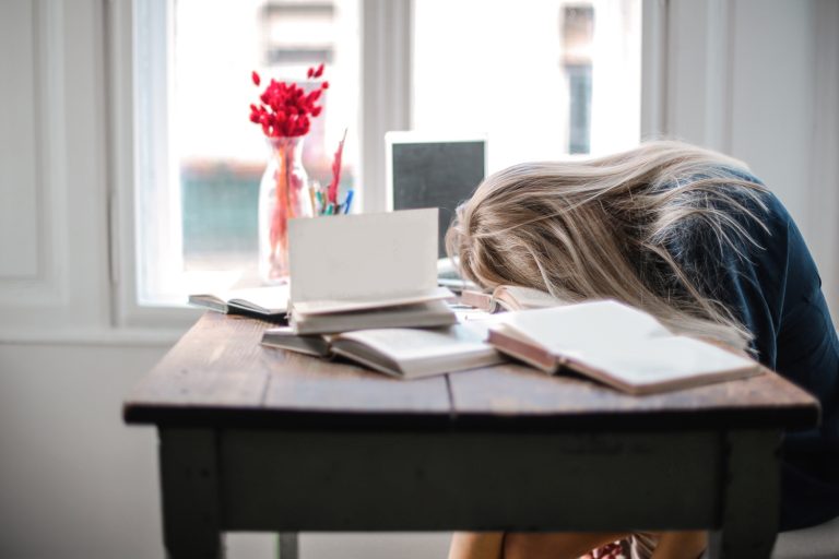 Photo of a blonde woman with head on desk looking depressed. Struggling with depression symptoms and have no support? Discover how depression counseling in Parkland, FlL can help support you.