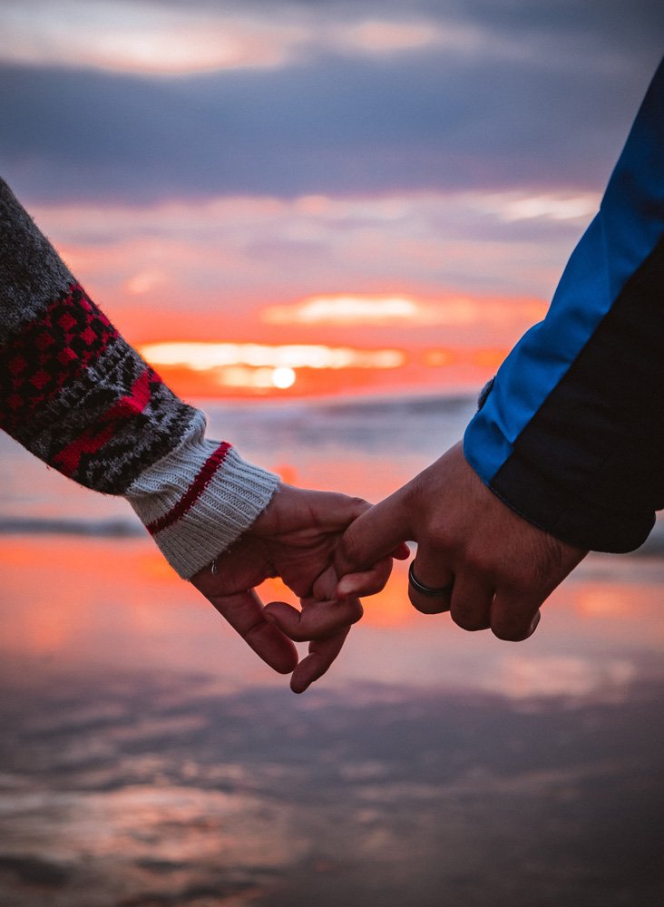 Photo of a couple's hands holding each other in front of water at sunset. Struggling with your depression symptoms in your relationship? Learn how depression counseling in Parkland, FL can help you and your partner reconnect.