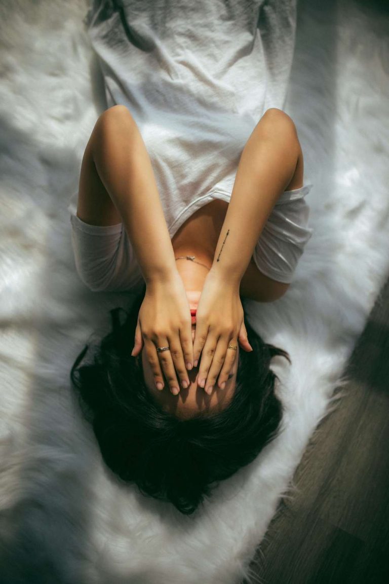 Photo of a woman laying on her bed with her hands covering her face. Discover the signs of ongoing depression and how you can stop them before it gets to bad with the help of depression counseling in Coconut Creek, FL.