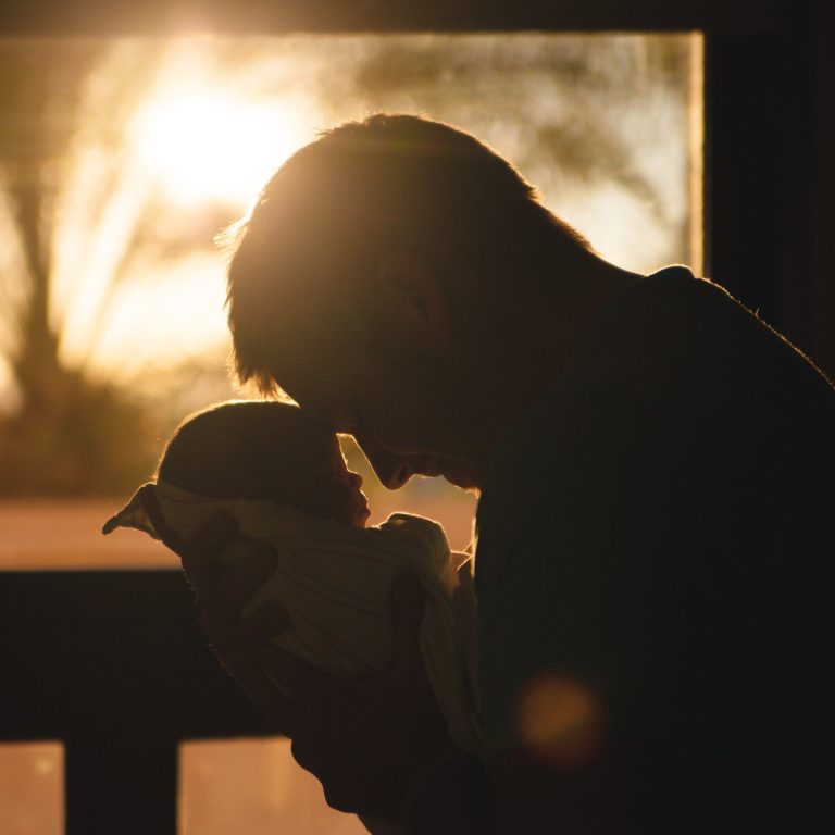 Photo of a man holding baby in sunset. Learn to effectively cope with your life transitions with the help of life transition therapy in Coconut Creek, FL.
