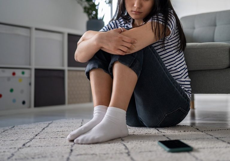 Shows a woman looking at her phone. Represents how an anxiety therapist in boca raton, fl can support you with cognitive behavioral therapy florida.