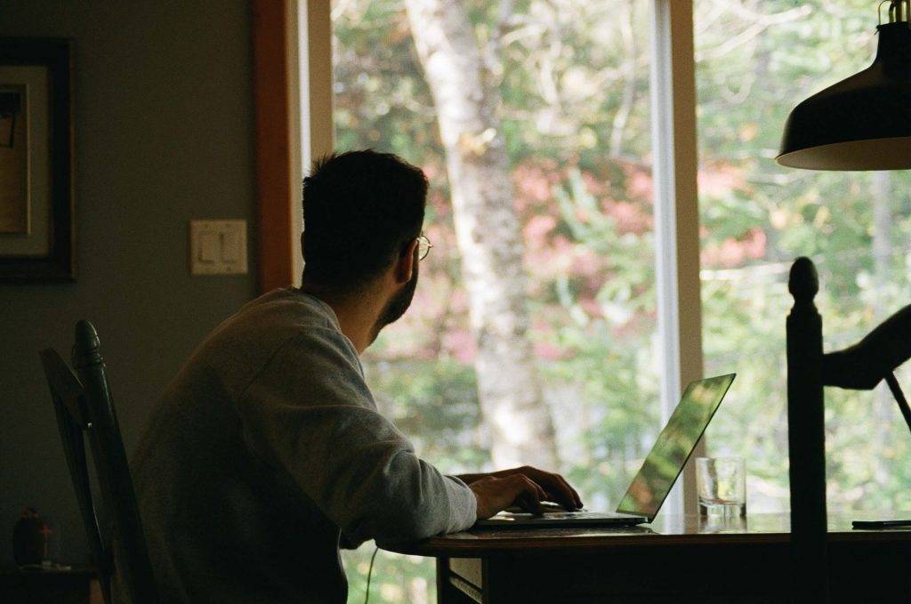 man looking out window | depression counseling in parkland, fl | depression therapist in parkland, fl | life transition therapy in parkland, fl | job loss depression | job loss and depression | coping with life changes and transitions | 33073 | 33067 | 33076 Image of a man working on a laptop while looking out a window. If you are struggling with the transition of a new job, learn how depression therapist in Parkland, FL can help you manage and cope with your emotions.