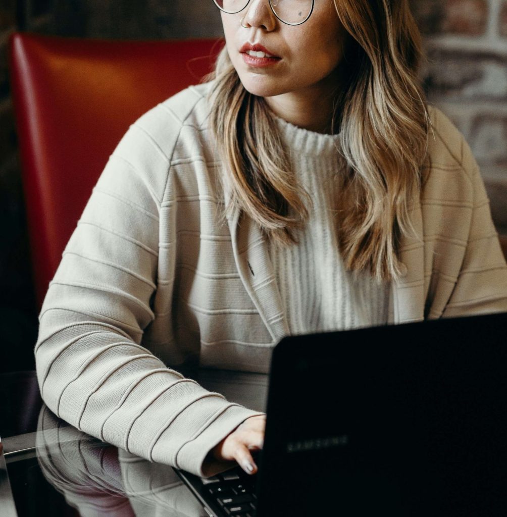 laptop | cbt therapy in parkland, fl | depression counseling in parkland, fl | cbt for depression in parkland, fl | cbt florida | cbt therapy | cbt therapist | 33073 | 33067 | 33076 Image of a woman wearing glasses and a sweater sitting in a red leather chair using a laptop. With CBT therapy in Parkland, FL you can learn to challenge negative thought patterns related to depression.