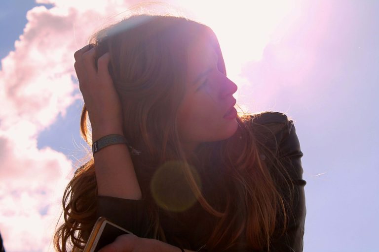 Image of a woman sitting outside on sunny day with her hand in her hair. If you are going through a life change, learn how CBT therapy in Parkland, FL can help!