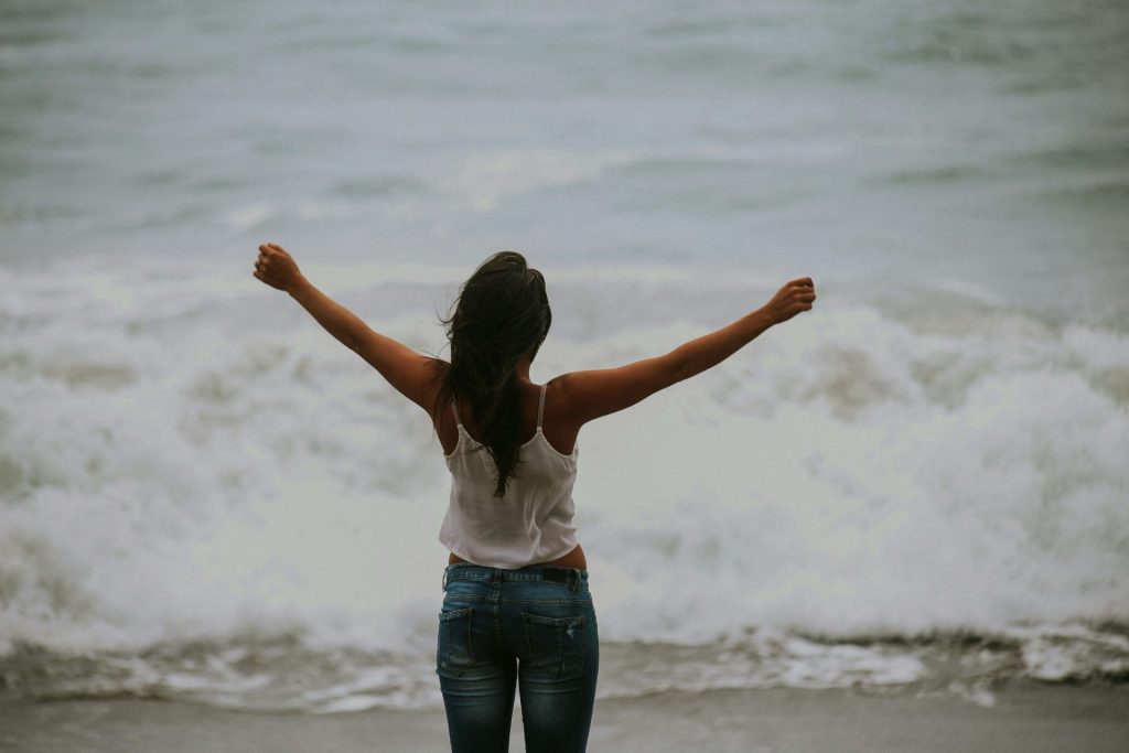 beach | cbt therapy in parkland, fl | depression counseling in parkland, fl | cbt for depression in parkland, fl | cbt florida | cbt therapy | cbt therapist | 33073 | 33067 | 33076 Image of a woman standing near the ocean with her arms up in the air feeling free. Learn positive ways to cope with your depression symptoms with CBT for depression in Parkland, FL.