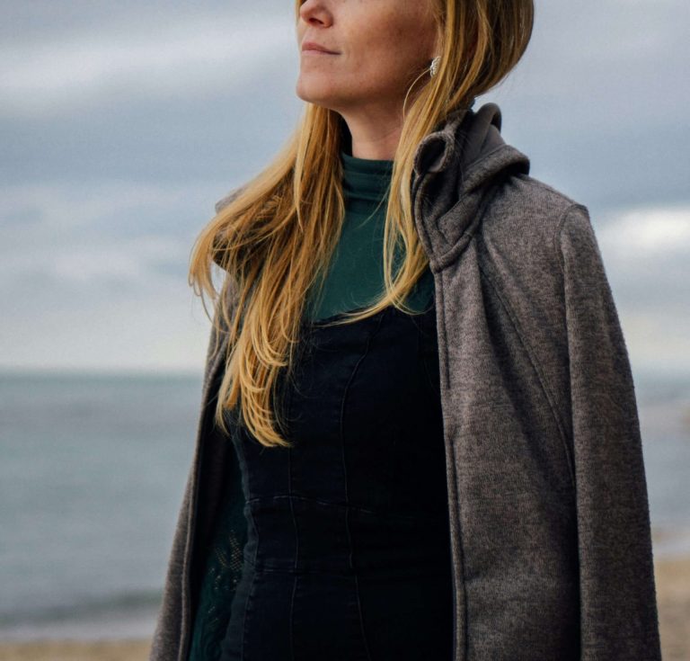 Image of a woman standing on a beach on a cloudy day. Discover how to manage your depression during a major life change with the help of depression counseling in Parkland, FL.