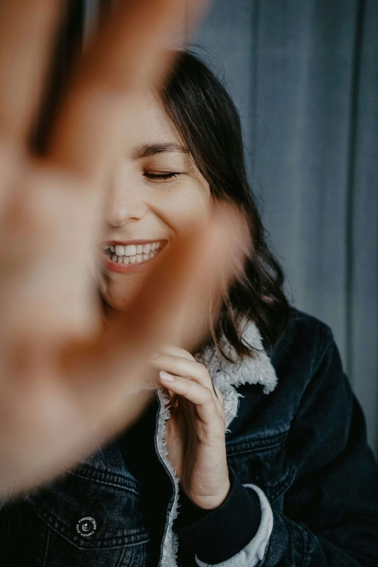 Image of a smiling woman, closing her eyes, and holding her hand in front of her face. Learn effective ways to deal with your depression from self-esteem issues with the help of depression, counseling in Parkland, FL.