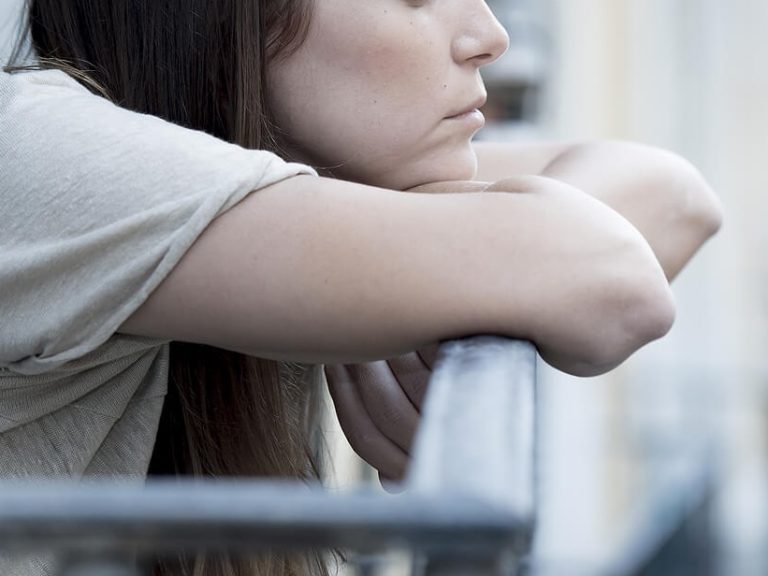 Image of a sad woman resting her head on her arms. Work with a skilled therapist at Invigorate Counseling in to overcome your depression symptoms with depression counseling in Parkland, FL.