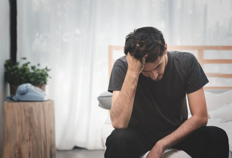 Image of an anxious man sitting on his bed with his hand in his hair. If you struggle with the Sunday scaries, work with a skilled anxiety therapist in Coconut Creek, FL to cope with your triggers.