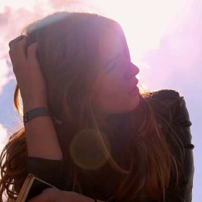 Image of a woman sitting outside on sunny day with her hand in her hair. If you are going through a life change, learn how CBT therapy in Parkland, FL can help!
